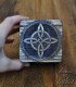 hand holding box showing the lid where the witch's knot symbol is laser engraved