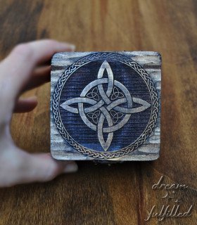 hand holding box showing the lid where the witch's knot symbol is laser engraved