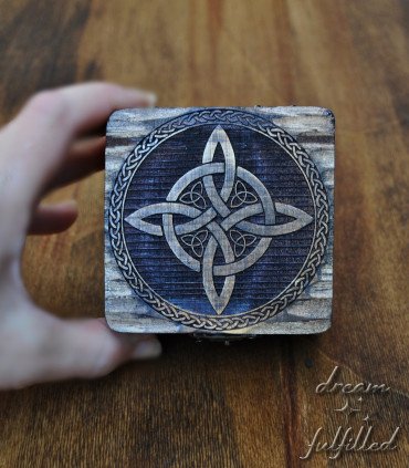 hand holding box showing the lid where the witch's knot symbol is laser engraved