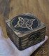 a hand holds a small dark wooden box engraved with a witch symbol