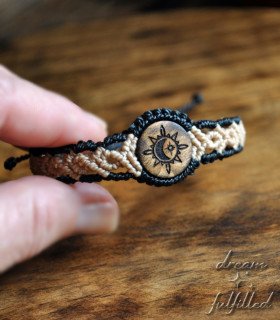 mano sujeta pulsera de hilo trenzado y madera grabada laser con símbolo de sol luna y estrella