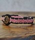 hand holding a black and pink braided thread bracelet and laser-engraved wood with a sun, moon, and star symbol