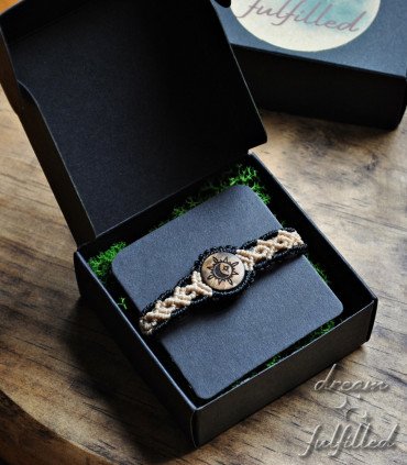 top view of a black and beige thread bracelet box and wood engraved with the symbol of the sun, moon, and star