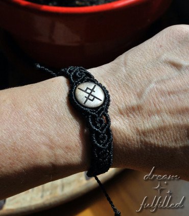 doll with a wooden bracelet and black macramé thread, engraved with a bindrune of eternal love