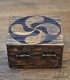 rear view of wooden box engraved with the lauburu symbol