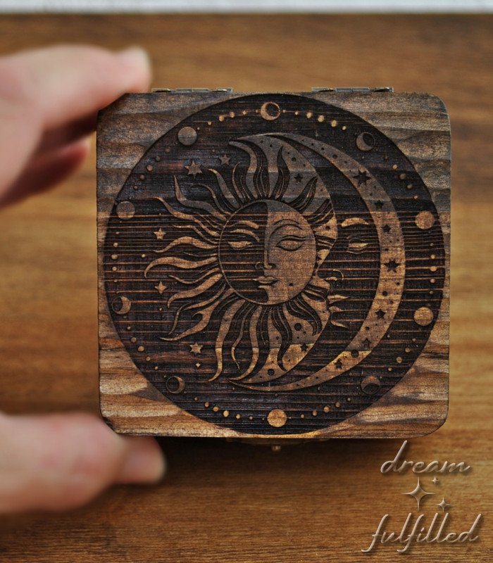 small wooden box engraved with sun, moon, stars, and lunar phases, top view of lid