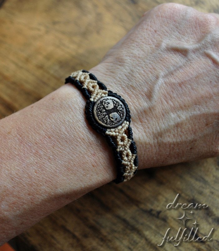 vista frontal de pulsera de madera e hilo trenzado de color negro y beis grabada con el símbolo del árbol de la vida