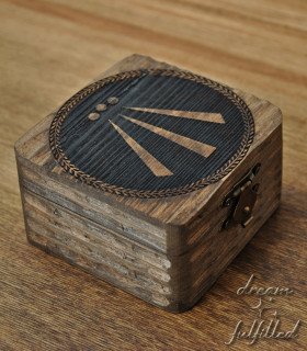 Dark wooden box with engraved Awen symbol in center and metal latch, top view showing details of engraving.