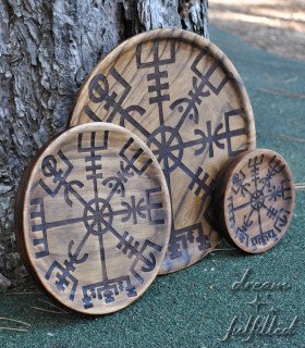 three wooden plates of different sizes engraved with the vegvisir, resting on a tree