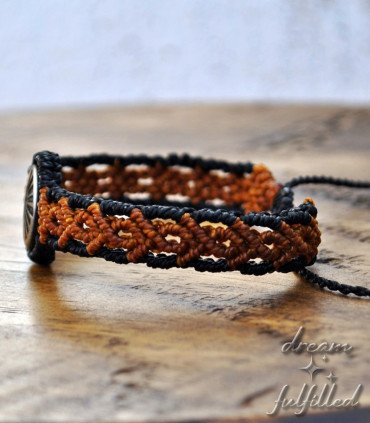 vista lateral de pulsera de madera e hilo trenzado de color marrón, grabada con el símbolo de la vieira del Camino de Santiago