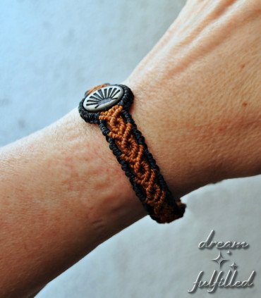 muñeca con pulsera de madera grabada con el símbolo de la vieira del Camino de Santiago