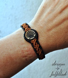 muñeca con pulsera del peregrino de madera e hilo trenzado de color marrón y negro